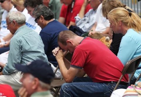 People pray for victims of the Aurora shooting during a Mitt Romney rally in New Hampshire Friday.Photo by Justin Sullivan/Getty