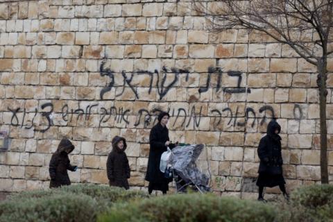 Woman walks past graffiti calling for Jewish women to dress modestly in Beit Shemesh, Israel. Photo by Getty Images.