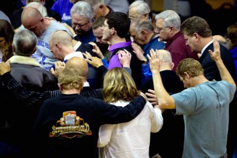 Residents pray during a worship service for the tornado-ravaged Harrisburg, Ill. Photo by Whitney Curtis/Getty Images. Photo by Whitney Curtis/Getty Images.