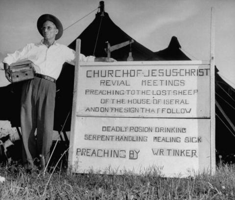 Snake handler W. R. Tinker standing beside sign for his 1948 revival meeting. (Photo by Francis Miller/Time Life/Getty Images.