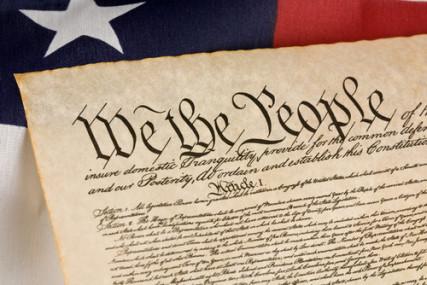 The U.S. Constitution with an American flag. Photo courtesy of Mark Hayes via Shutterstock