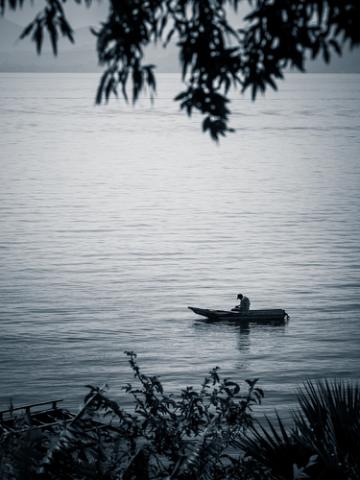 Small rowing boat with single fisherman on lake. davesimon / Shutterstock davesimon / Shutterstock
