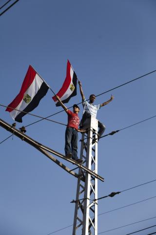 Two young Egyptians on top of a tramway pole holding Egyptian flag. Photo via Shutterstock, by George Nazmi Bebawi