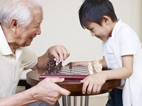 A grandfather and grandson play chess. Image courtesy imtmphoto/shutterstock.com