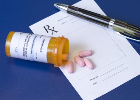 Prescription bottle, pink pills, pen, and prescription pad on royal blue background. Photo:Sherry Yates Young LPN / Shutterstock
