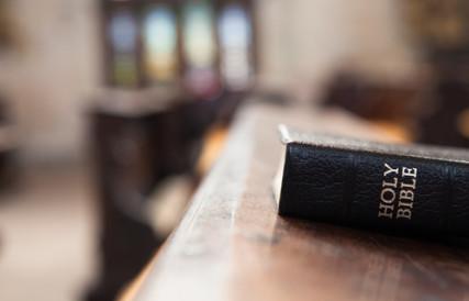 Holy Bible on a wooden church bench Photo courtesy of Magdalena Kucova via Shutterstock