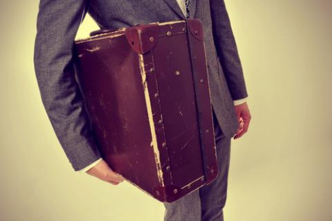 A young man carries an old suitcase. Image courtesy nito/shutterstock.com. A young man carries an old suitcase. Image courtesy nito/shutterstock.com.