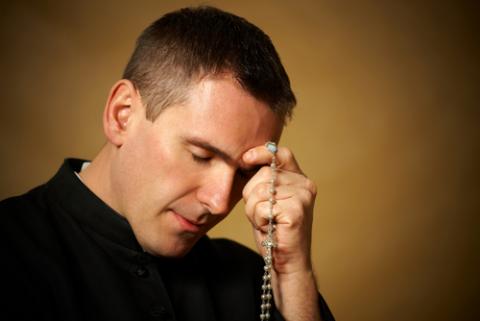 Praying priest with rosary in his hands. Monika Wisniewska / Shutterstock Monika Wisniewska / Shutterstock