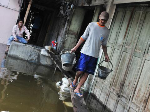 A laborer in Thailand in 2011 after the country experienced its worst flooding in years. Photo via 1000 Words/shutterstock.com
