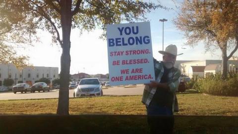 A man in a cowboy hat holds a sign of support outside of a mosque in Irving, Tx