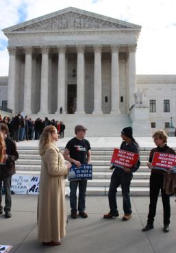 Demonstrators hold signs in front of the Supreme Court on Nov. 6, 2013 during oral arguments of Greece v. Galloway. RNS photo