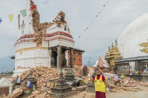 A volunteer stands in front of a collapsed temple at the Swayambhunath temple complex in Nepal. Photo via Vishal Arora / RNS Photo via Vishal Arora / RNS