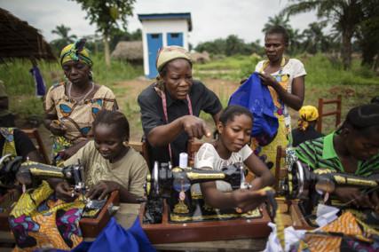 Sister Angélique Namaika (standing, in black), assists women with making clothing. Via RNS. Photo by Brian Sokol/courtesy UNHCR