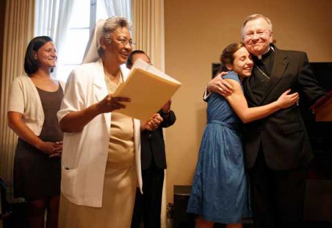 Paige LaCour, second from right, hugs Archbishop Gregory Aymond. RNS photo: Rusty Costanza / The Times-Picayune RNS photo by Rusty Costanza / The Times-Picayune