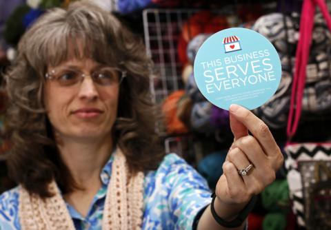 Business owner Elizabeth Ladd holds a sticker she plans to display outside her store. Photo via REUTERS / Nate Chute / RNS Photo via REUTERS / Nate Chute / RNS