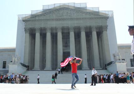 A man exits the Supreme Court building with an American flag after its rulings on same-sex marriage. RNS photo: Adelle M. Banks