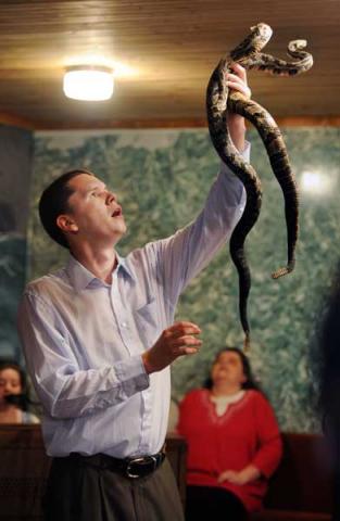 Pastor Andrew Hamblin of Tabernacle Church of God in LaFollette, Tenn. holds up two snakes. Photo: RNS/by Shelley Mays/USA Today