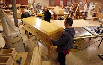 Novices Joseph Eichorn, left and Dustin Bernard move a handmade wooden casket. Photo via RNS, by Ted Jackson/The Times-Picayune.