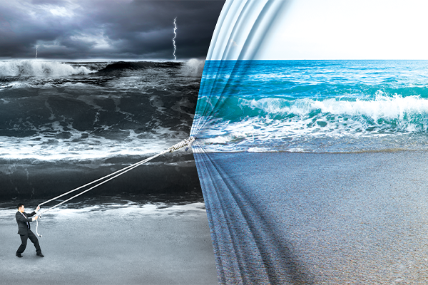 A. man pulling what looks like a curtain, bringing in an image of a calm beach scene over a stormy scene.