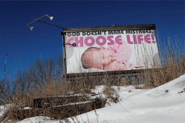 An image of a baby appears on a billboard with the words "God doesn't make mistakes; choose life"