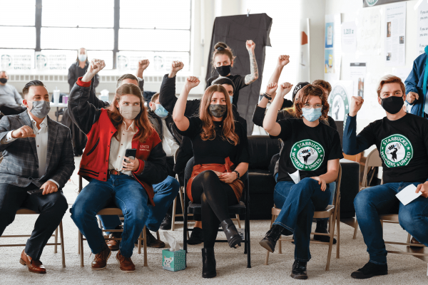 Starbucks employees hold raised fists in the air during a union vote