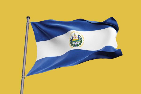 A picture of El Salvador's blue and white national flag, flying from a flag pole against a yellow backdrop.