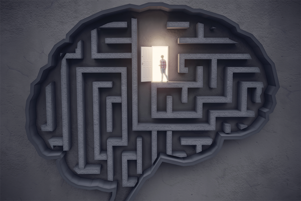 A birds-eye view of a textured gray background overlaid with a maze in the shape of a brain. In the top third of the brain, a figure silhouetted by golden light walks through an open door.