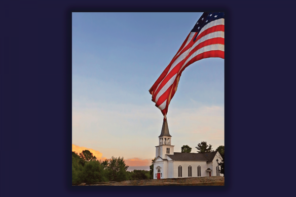 The image shows a white church with a steeple over a sunset and there is an American flag waving. 