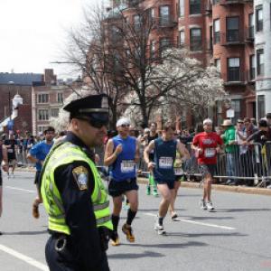 A Police officer stands by as runners pass during the 2013 Boston Marathon. Phot