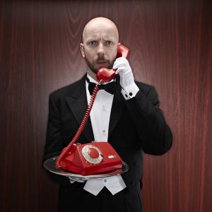 Butler with a red telepfone on a silver tray. Photo via Getty Images. 