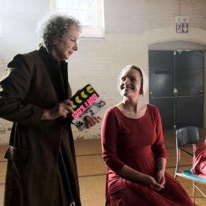 Margaret Atwood holds a slate while laughing with Elizabeth Moss during filming of The Handmaid's Tale series. 