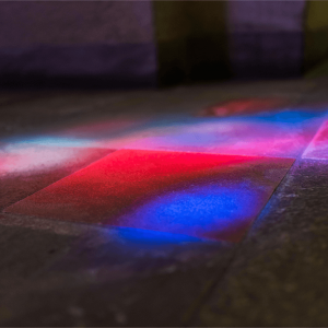 Closeup of red and blue light from a stained glass window on a stone floor.