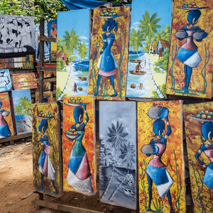 Paintings of AfroLatinx women depicted in bright blues on display at an outdoor market.