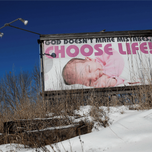 An image of a baby appears on a billboard with the words "God doesn't make mistakes; choose life"