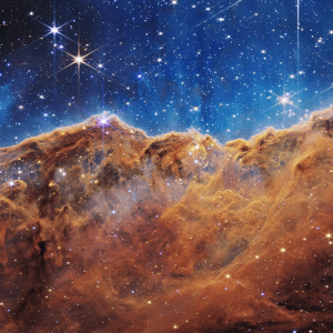 An image from the James Webb Space Telescope shows star formation with orange dust against a blue background.