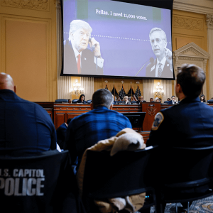 Members of the U.S. House Select Committee investigating the Jan. 6 attack on the U.S. Capitol sit beneath an image showing former President Donald Trump speaking on the telephone in the Oval Office during the the committee's final meeting on Dec. 19, 202