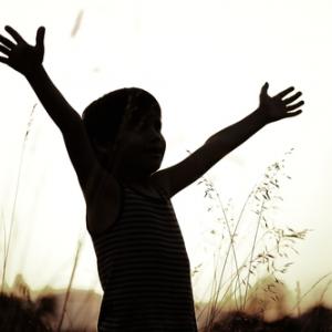 Young boy reaches to the sky. Photo courtesy Zurijeta/shutterstock.com