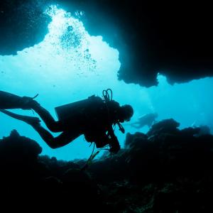 A scuba diver makes their way through an underwater cave