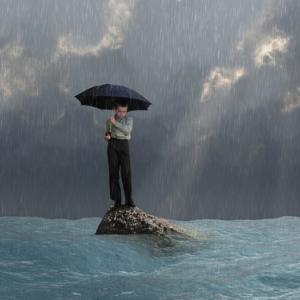 Man with an umbrella in a flood, photobank.kiev.ua / Shutterstock.com