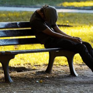 An impoverished young man man on a bench. Photo courtesy Dariush M/shutterstock.