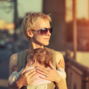 A mother carries her child through a city. Image via Konstantin Sutyagin/shutter