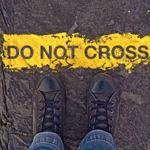 Sneakers on asphalt road and "Do Not Cross" sign. Image courtesy igor.stevanovic