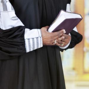 Female clergy holding a Bible, glenda / Shutterstock.com