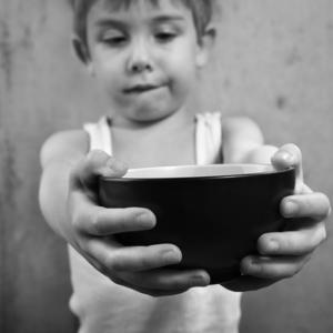 Child holding empty bowl, Suzanne Tucker / Shutterstock.com