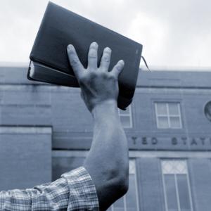 Man holding up Bible in front of court house, Cheryl Casey / Shutterstock.com