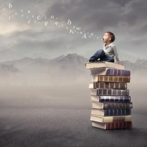Photo: Child sitting on stack of books, olly / Shutterstock.com
