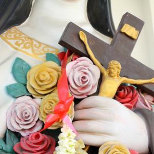Flowers and crucifix in the hand of holy women. Image via GOLFX/shutterstock.com