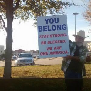 A man in a cowboy hat holds a sign of support outside of a mosque in Irving, Tx