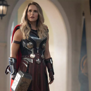 Natalie Portman holds a large hammer and is dressed as Thor.