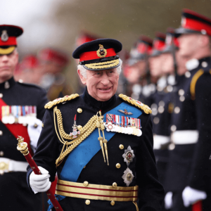 King Charles III is shown in decorated military regalia in front of uniformed British soldiers.